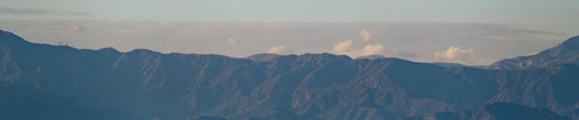 Panoramic mountain range at sunrise with layered blue ridges and sky suggesting outdoor cleaning gear Maitenance tips guide
