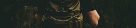 Person wearing olive green versatile tactical backpacks outdoors against dark forest background