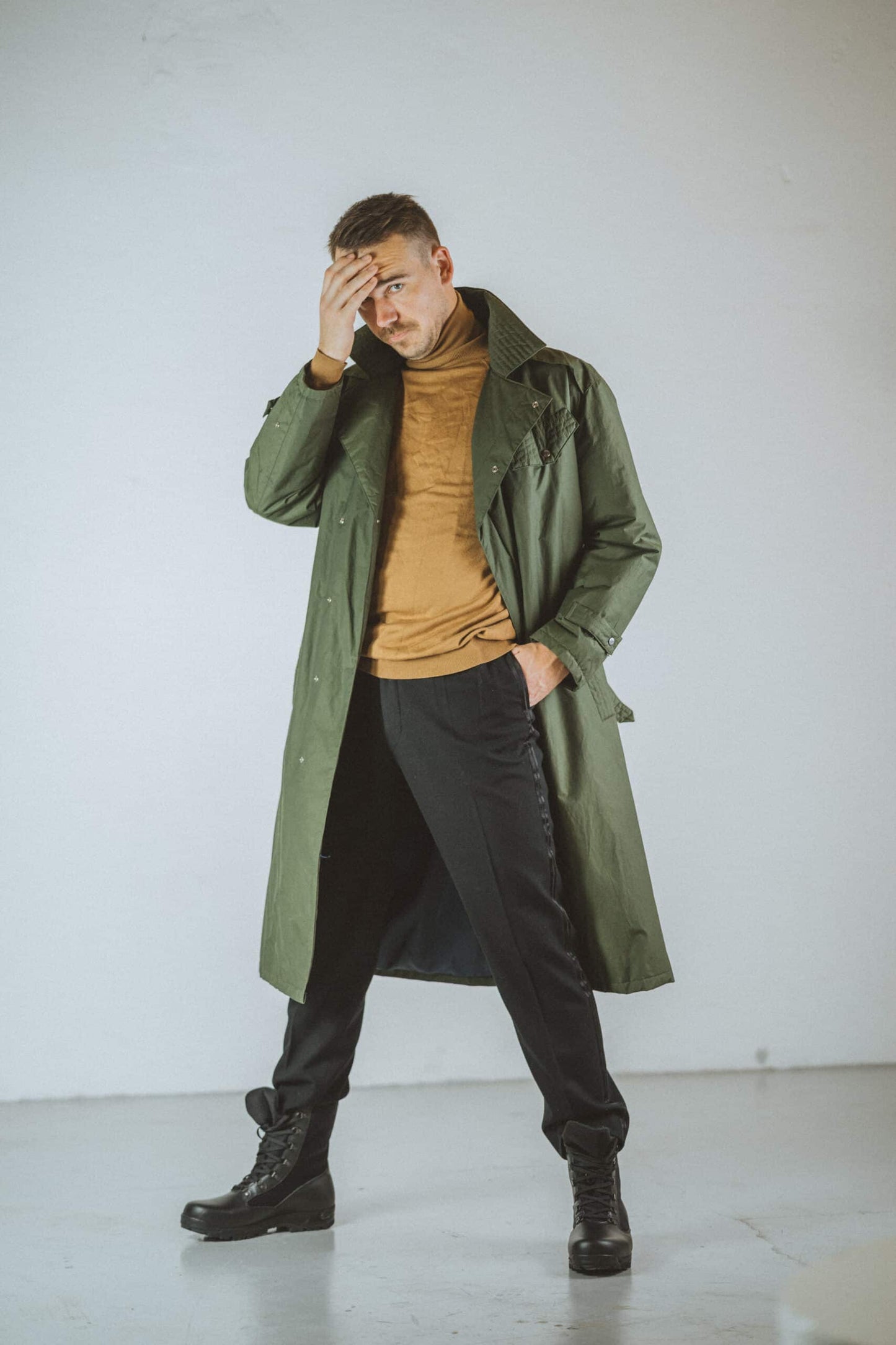 Stylish man wearing a long coat and black pants with desert hiking boots black for outdoor adventures