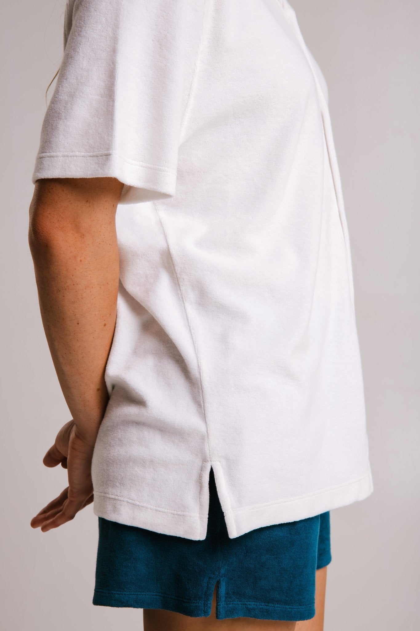 Side view of a person wearing a white panda terry t-shirt white by Sossu with short sleeves and side slits