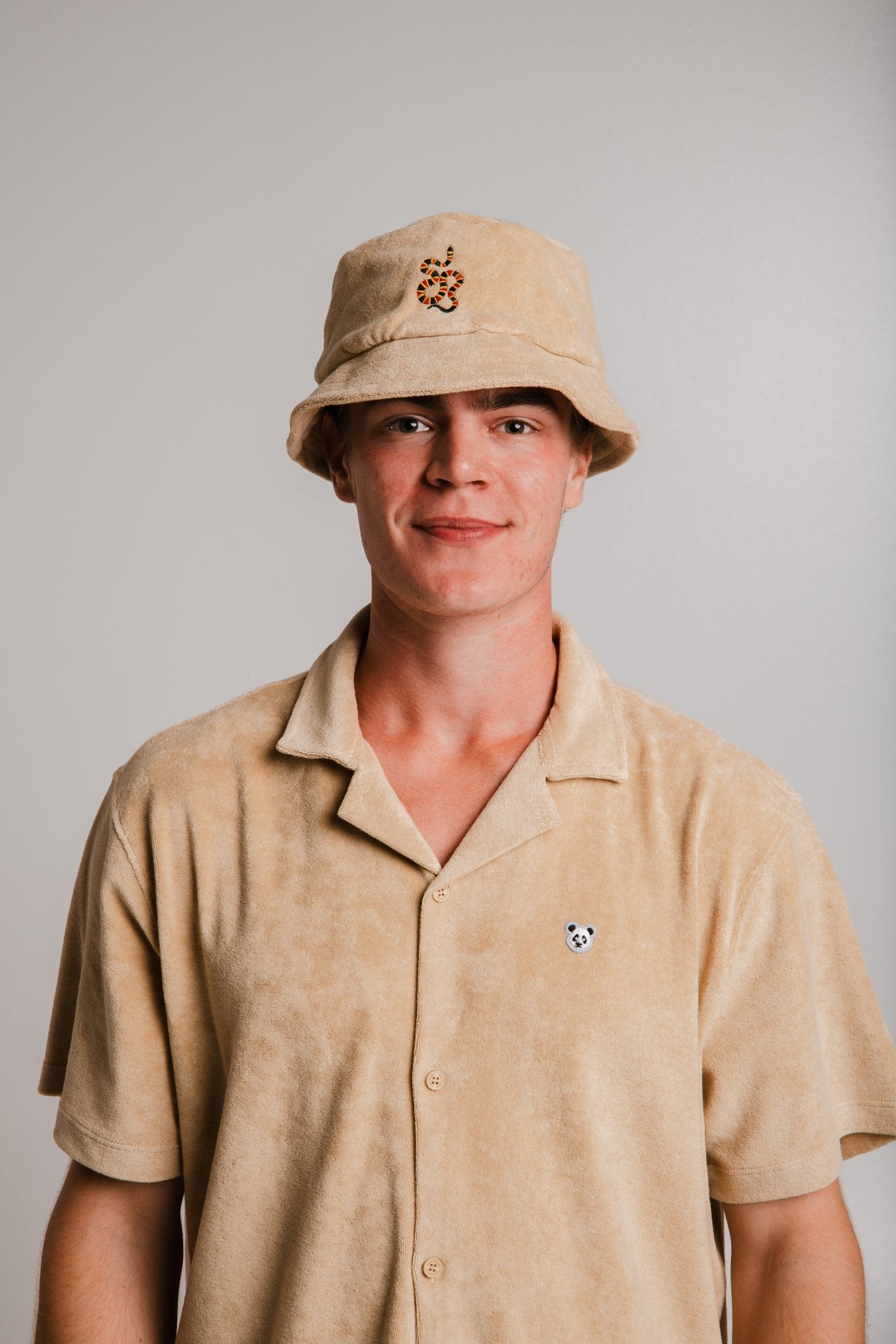 Light brown panda t-shirt by Sossu worn by a young man with matching bucket hat