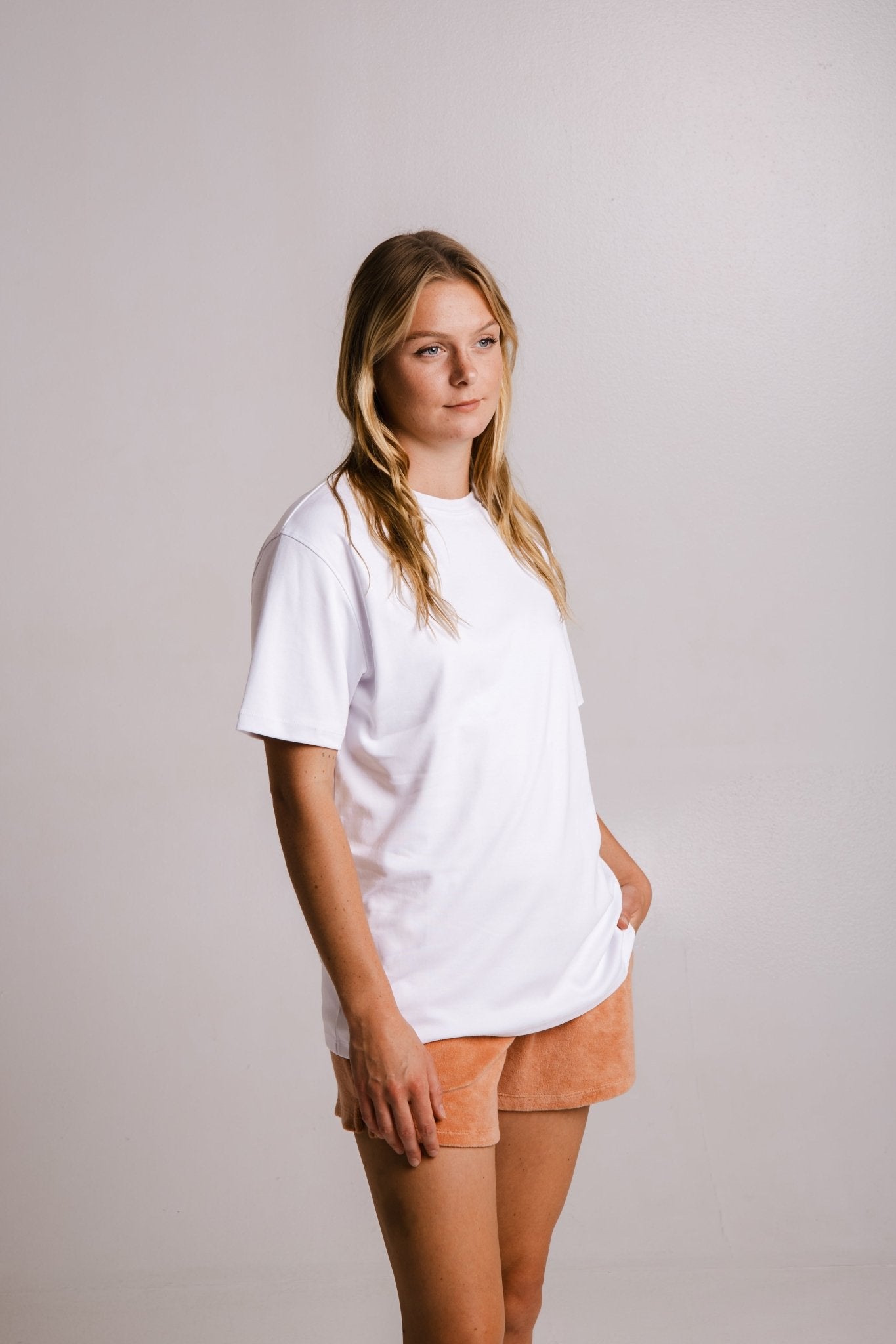 Sossu heavy fabric regular fit unisex t-shirt in white worn by a woman with tan shorts